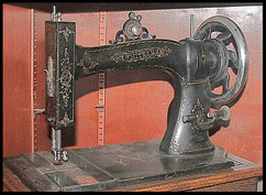 Vintage White Sewing Machine Company model with intricate gold detailing on a black body, displayed on a wooden table.