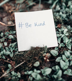 A note saying Be Kind, on a nature background