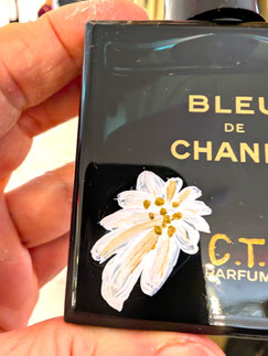 Nahaufnahme eines Bleu de Chanel Parfümflakons mit handbemalter Edelweiß-Illustration und Gold-Initialen, exklusiv gestaltet bei Breuninger München