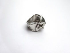Une bague en argent comme déformée est vue de trois-quarts.