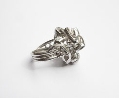 Une bague au design à spirales est exposée de profil sur fond blanc.