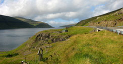 Sehenswürdigkeiten Färöer Inseln: Eine schmale Landstraße führt entlang eines malerischen Fjordes.