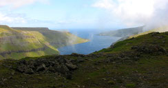 Blick auf steil abfallende Küstenhügel und dem azurblauen Wasser des ruhigen atlantischen Ozeans.
