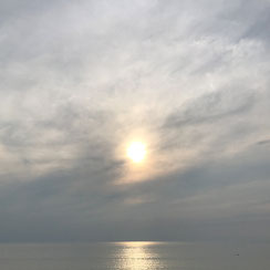 De zon in de zee zien zinken, maar de wolken kleuren de wereld al zilver, nog even glanst de zon op het water