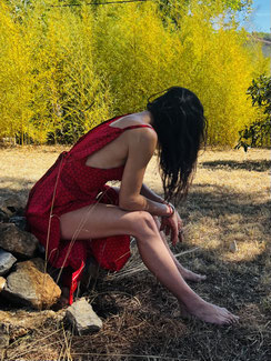 Robe longue en soie échancrée sur les côtés, portée par l’artiste Nine. Modèle dessiné par elle et confectionné artisanalement en Inde par des femmes artisanes. Une pièce fluide et sensuelle qui sublime la silhouette avec légèreté.