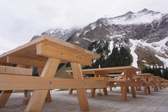 Tischgarnitur Dartet aus Lärche, handgefertigte Gartenmöbel für den Aussenbereich vor alpiner Bergkulisse.