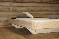 Schwebendes Balkenbett aus massivem Arvenholz, handgefertigt mit klarer Form und natürlicher Holzmaserung.
