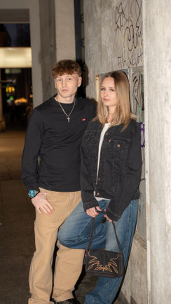  Junges Paar in Hausdurchgang. Er mit beiger Jeans und schwarzem Pulli. Sie mit Blue Jeans und schwarzer Jacke.
