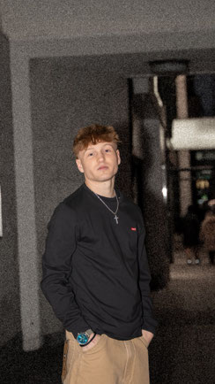 Junger Mann in beiger Jeans und schwarzem Pulli von Levis.