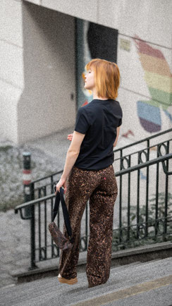 Junge Frau auf Stiegen mit Tasche in der Hand.