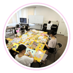 テーブルの上で絵を描いている子ども達