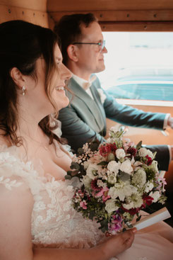 Braut mit Blumenstrauß und Bräutigam lachen im Oldtimer Feuerwehrauto, Hochzeit Herxheim Südpfalz