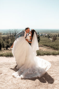 Bräutigam hebt lachende Braut hoch vor Weinbergpanorama der Villa Ludwigshöhe Edenkoben, After-Wedding-Shooting Südpfalz