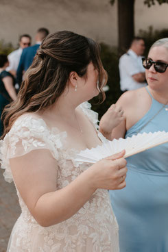 Braut mit weißem Fächer beim sommerlichen Hochzeitsempfang in Herxheim-Hayna, Hochzeitsfotografie Südpfalz