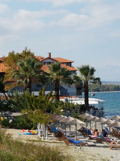 alt="Platamonas am Fuße des Olymp-Gebirges: Langer Kies-Sandstrand mit türkisem Meer, byzantinischer Burg auf dem Hügel und schneebedeckten Olymp-Gipfeln im Hintergrund – idealer Urlaubsort in Griechenland"