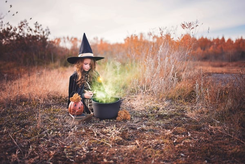 une petite fille deguisee en sorcier devant un chaudron 