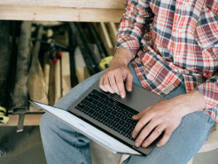 Ein Heimwerker mit einem Laptop vor einem Arbeitstisch