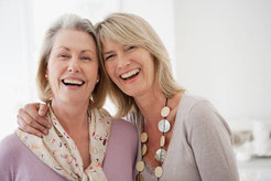 2 Frauen, mittleren Alters stehen eng aneinender. die rechte Frau legt wohlwollend ihre Hand auf die Schulter der linken Frau. Beide lächeln in die Kamera