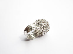 Une bague boule en argent ajourée est vue de trois-quarts.