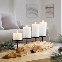 Moderner Kerzenhalter mit vier großen weißen Kerzen auf einer natürlichen Holzbasis, stilvolle Weihnachtsdekoration von formano.