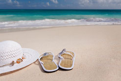 Content für Betriebsferien Uralubsfeeling am Strand und Meer mit Strandlatschen und Sonnenhut liegend im Sand