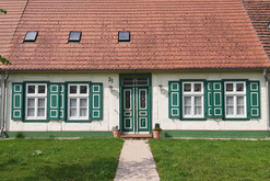 Ein kleines weißes Haus mit grünen Fensterläden