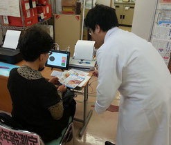 患者に血管年齢測定の説明をする天満カイセイ薬局の大上直人薬局長（右）