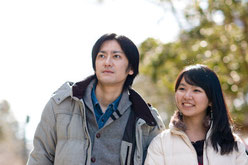 明るい日差しの中、笑顔で同じ方向を見つめる夫婦