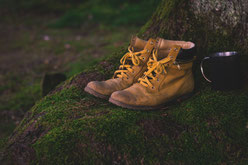Schuhe und eine Tasse auf einem moosbedecken Fels