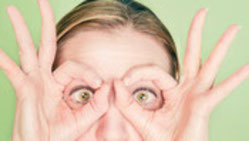 Frau formt mit den Fingern eine Brille und sieht durch