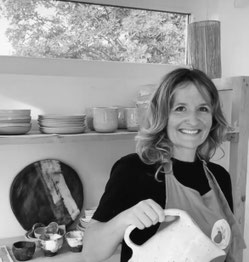 Portrait d’Alexandra Coutand dans son atelier, entourée de pièces en céramique texturées, révélant son travail sur la matière, les reliefs et la construction sculpturale.