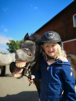 Lachendes Kind mit einem Pony, das eine Grimasse schneidet