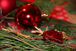 Adventsdeko mit Tannengrün, roten Weihnachtskugeln und Strohstern