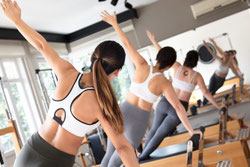 Frau trainiert gemeinsam mit anderen Teilnehmern in einem Fitnesskurs zur Förderung von Muskelkraft und Beweglichkeit.