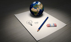 Une feuille de papier avec une ampoule dessinée, un crayon, une gomme et la mappe monde posés sur une table