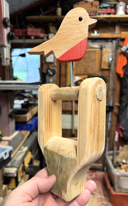 Handmade wooden robin decoration mounted on reclaimed wooden fork handle in workshop