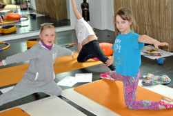 Im Kinderyoga finden drei Mädchen eine schöne Übung, die zeigt wie ein Küken aus dem Ei schlüpft.