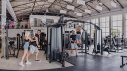 Fitnessstudio Gym OHZ mit modernen Geräten, Trainierenden und Trainer in heller Trainingshalle.