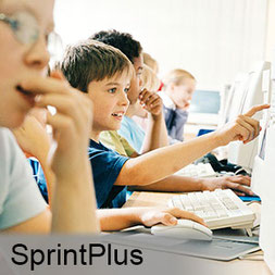 Mehrere Schüler sitzen nebeneinander an Computern, einer zeigt auf den Bildschirm, andere beobachten aufmerksam