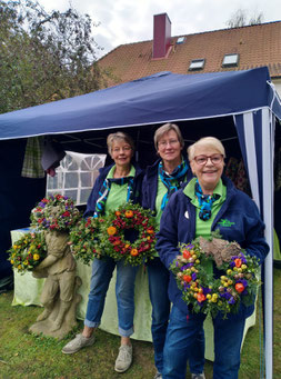 3 LandFrauen vor einem Verkaufsstand mit Herbstkränzen