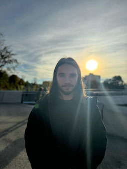 Robin Wußler in schwarzer Jacke vor der untergehenden Sonne.