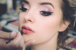 Frau wird mit dezentem Lippenstift geschminkt.