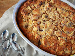 eine ovale Auflaifform mit Brotpudding, im Vordergrund liegen mehrere Dessertlöffel