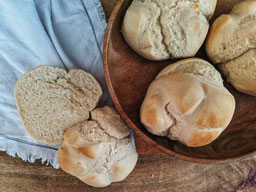 auf einem Holztisch liegen 3 Zack-Zack-Brötchen in einer Holzschale, daneben ist ein aufgeschnittenes Brötchen zu sehen Zack Zack Brötchen zum Frühstück - ganz einfach - ganz schnell
