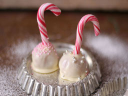 2 weiße Cake Pops WinterWunderLand in denen jeweils eine Zuckerstange steckt liegen auf einer kleinen Tarteform