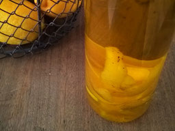 ein Glas mit Zitronenöl, oben links sieht man 2 Zitronen