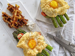 auf 2 weißen Porzellanplatten liegen jeweils 1 Cloud Eggs auf Ciabatta mit ErbsenHummus und grünem Spargel