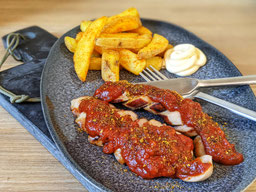 ein dunkelgrauer Teller mit Pommes Mayo und Currywurst - selbstgemachte Currywurst