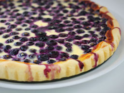 eine Blaubeer Tarte mit Eierguss auf einem weißen Teller
