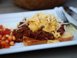 auf einem weißen, eckigem Teller liegt eine Scheibe Toast mit sloopy joe, einer Hackfleischsauce, darauf liegt eine Portion Rührei